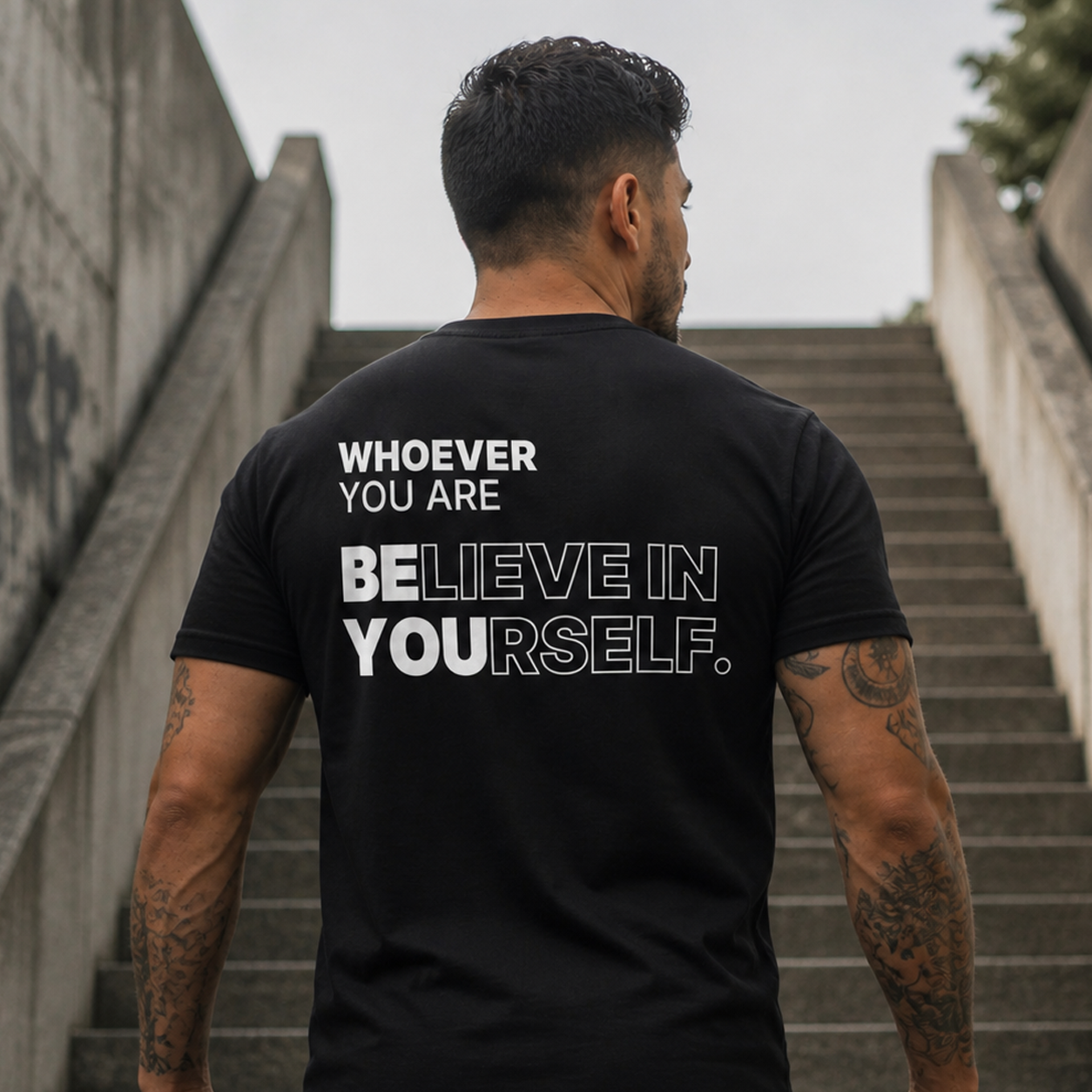Person wearing a black Believe in Yourself motivational t-shirt in an urban setting