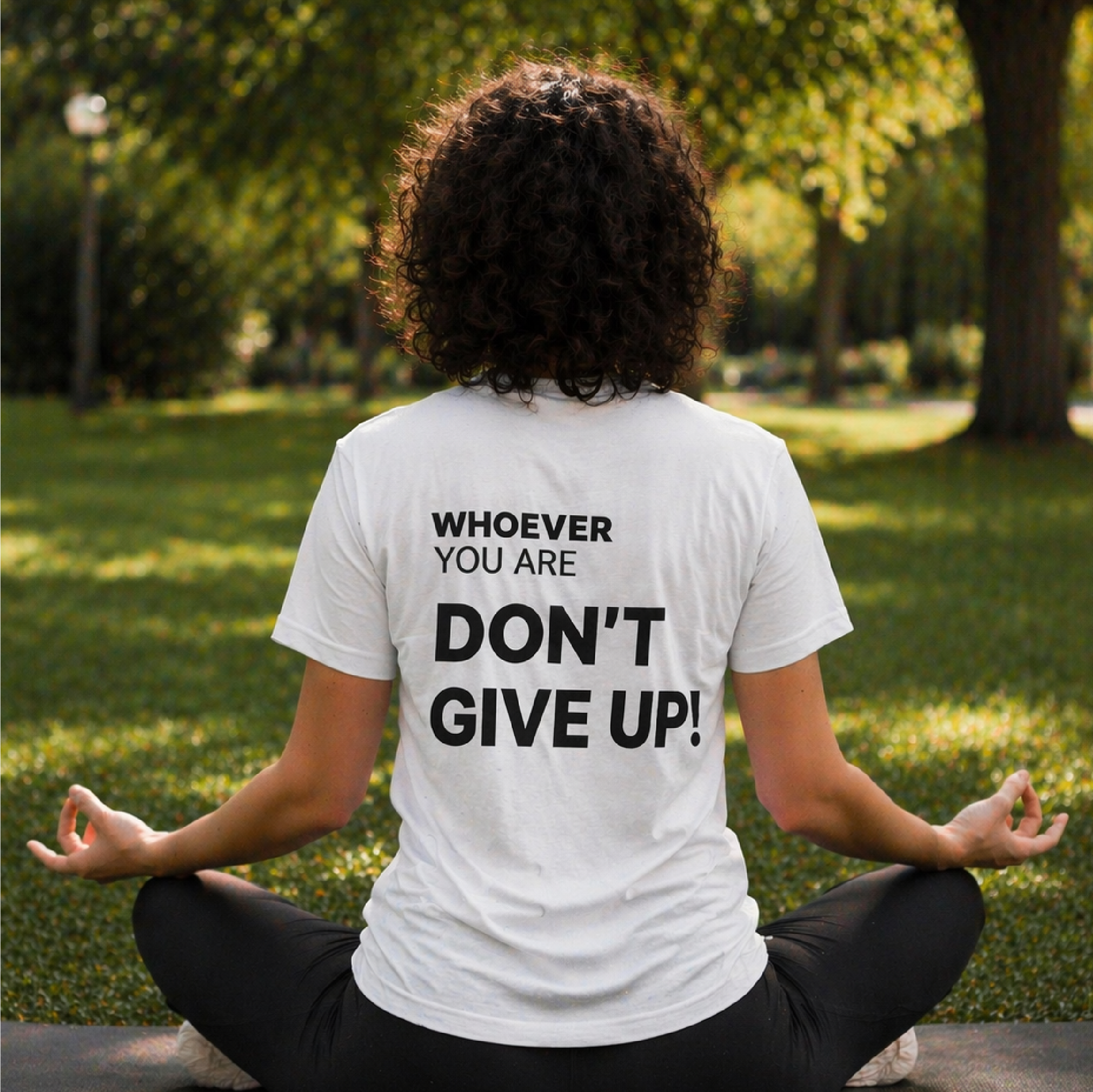 Person wearing a white Don’t Give Up! motivational t-shirt outdoors with back print visible
