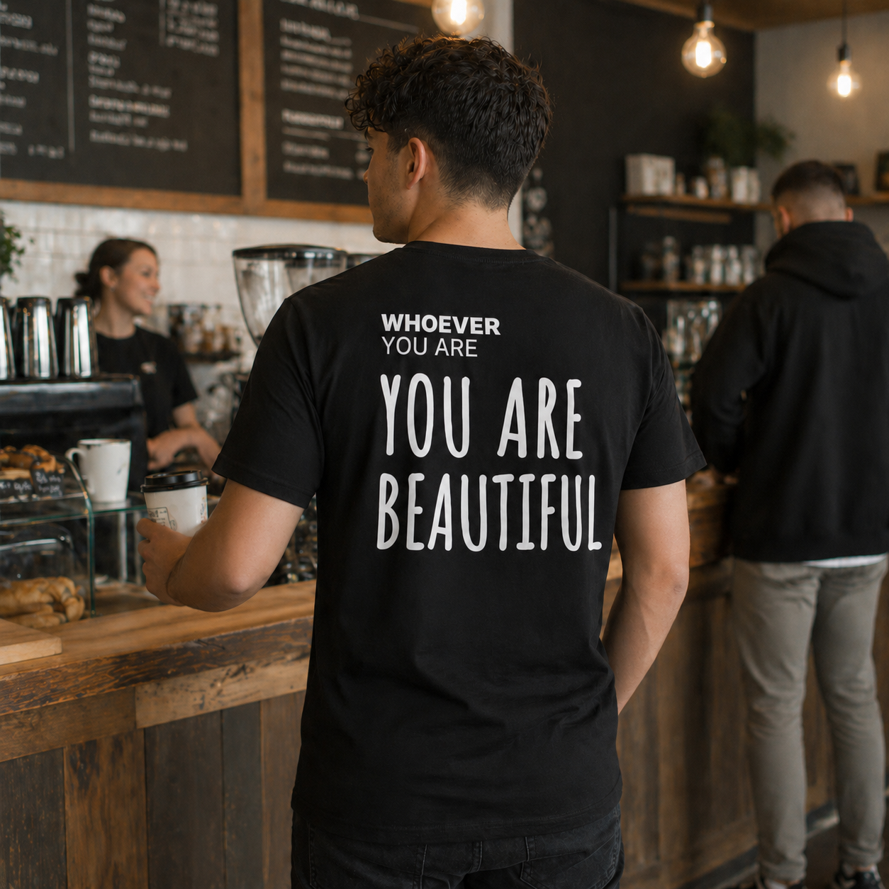 Person wearing a black You Are Beautiful kindness t-shirt indoors with back print visible