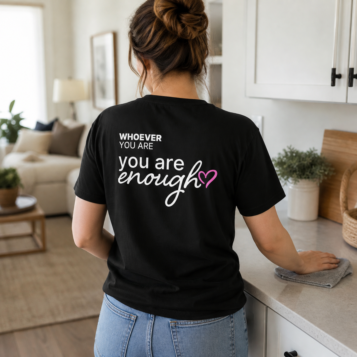 Person wearing a black You Are Enough kindness t-shirt with meaningful back print at home