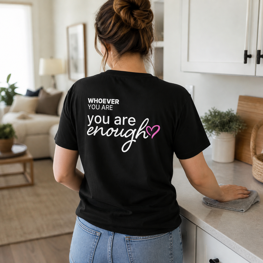 Person wearing a black You Are Enough kindness t-shirt with meaningful back print at home