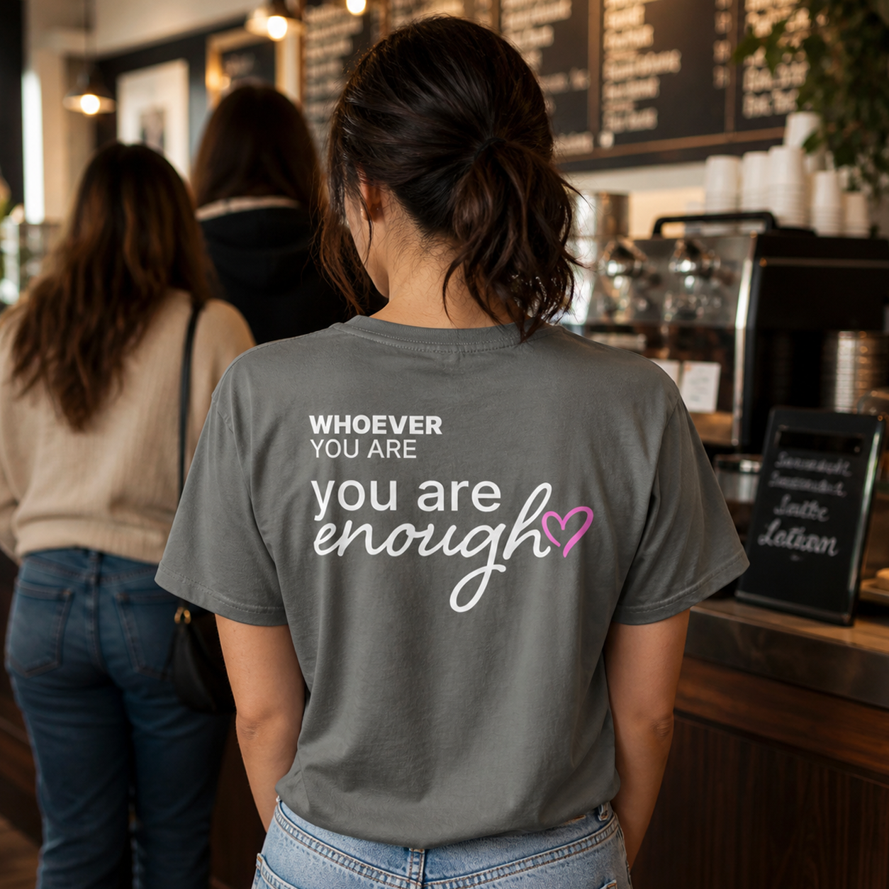 Person wearing a gray You Are Enough kindness t-shirt in a casual public setting